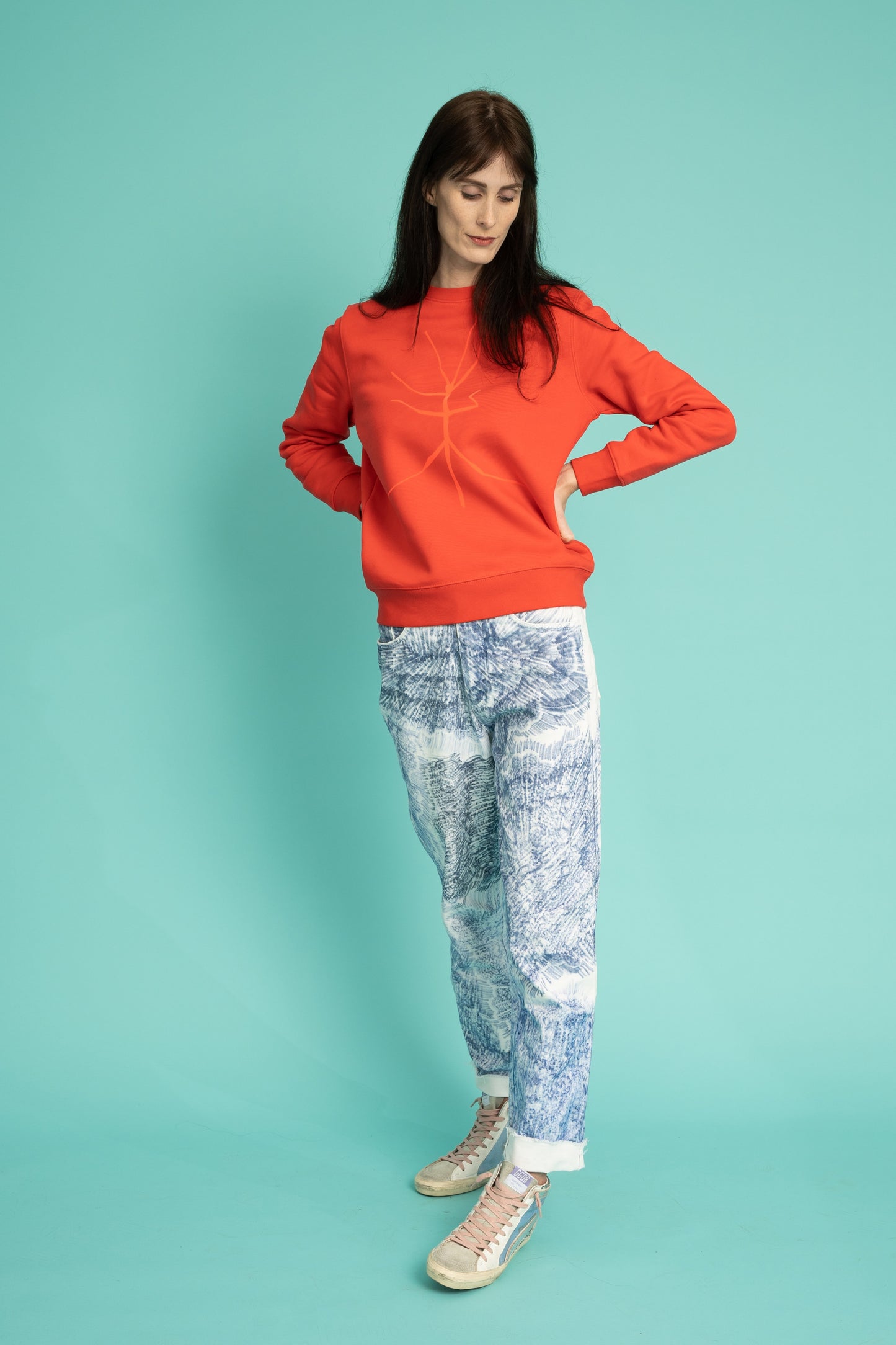 A slightly orange-red sweater and a walking stick
