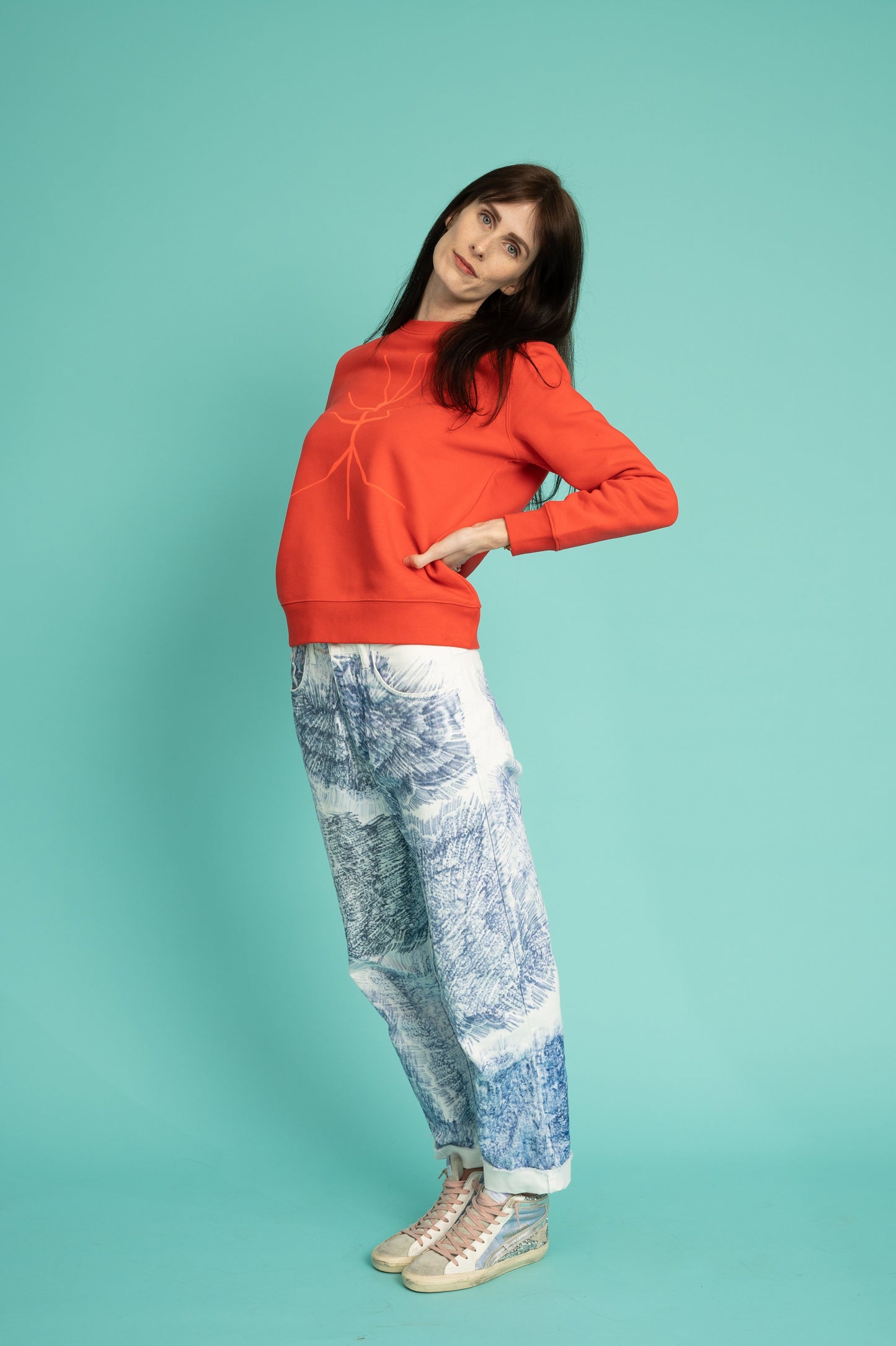 A slightly orange-red sweater and a walking stick