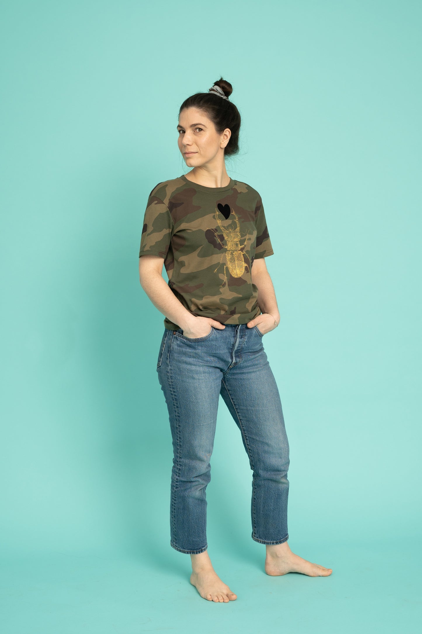 Golden scarab with black plush heart on a military pattern tee