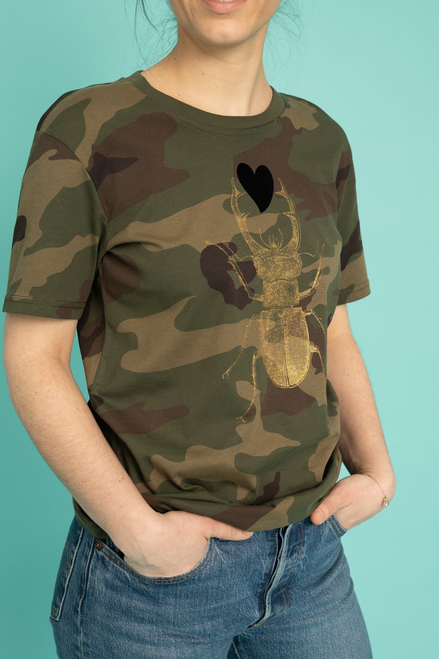 Golden scarab with black plush heart on a military pattern tee