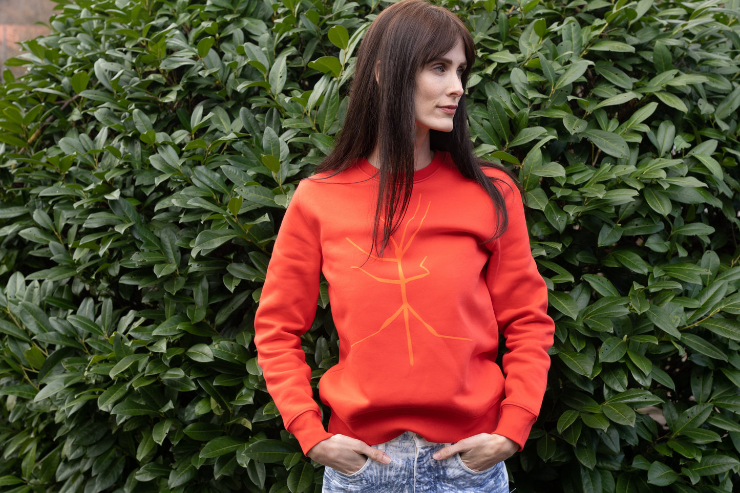 A slightly orange-red sweater and a walking stick