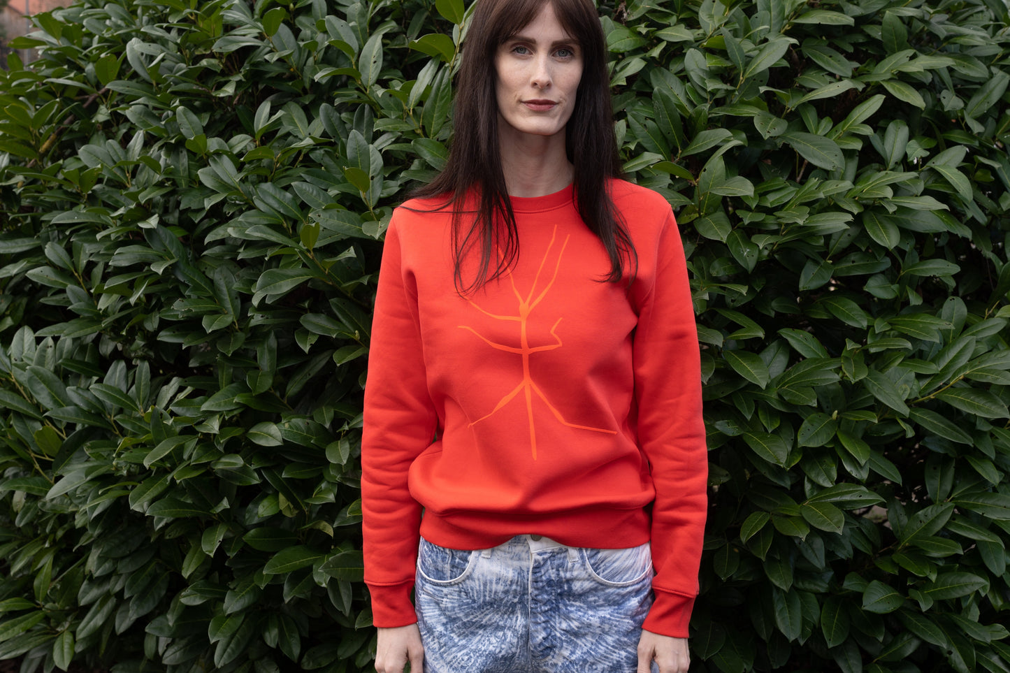 A slightly orange-red sweater and a walking stick