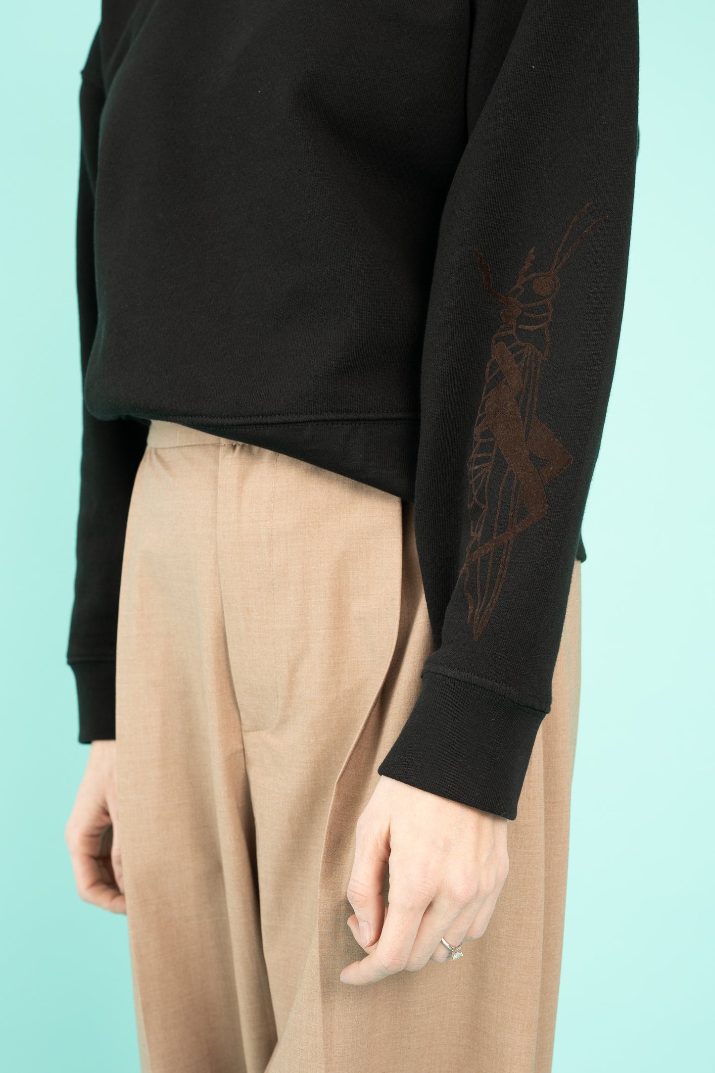 Black cropped crew neck sweatshirt with a grasshopper on the sleeve