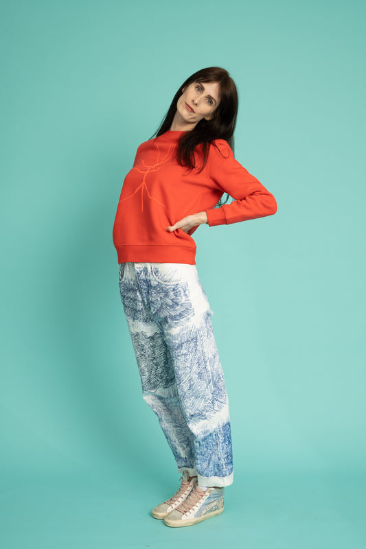 A slightly orange-red sweater and a walking stick