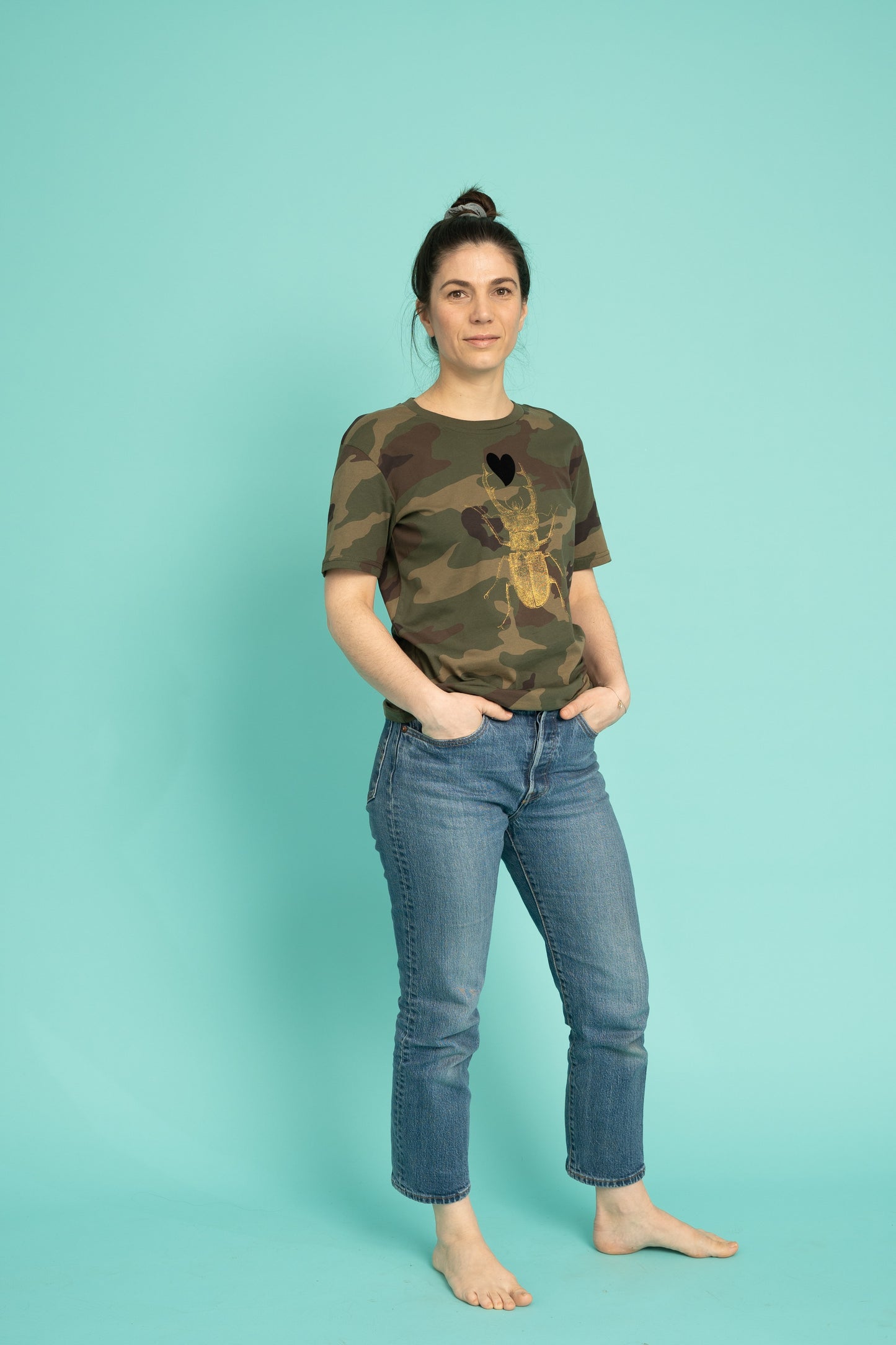 Golden scarab with black plush heart on a military pattern tee