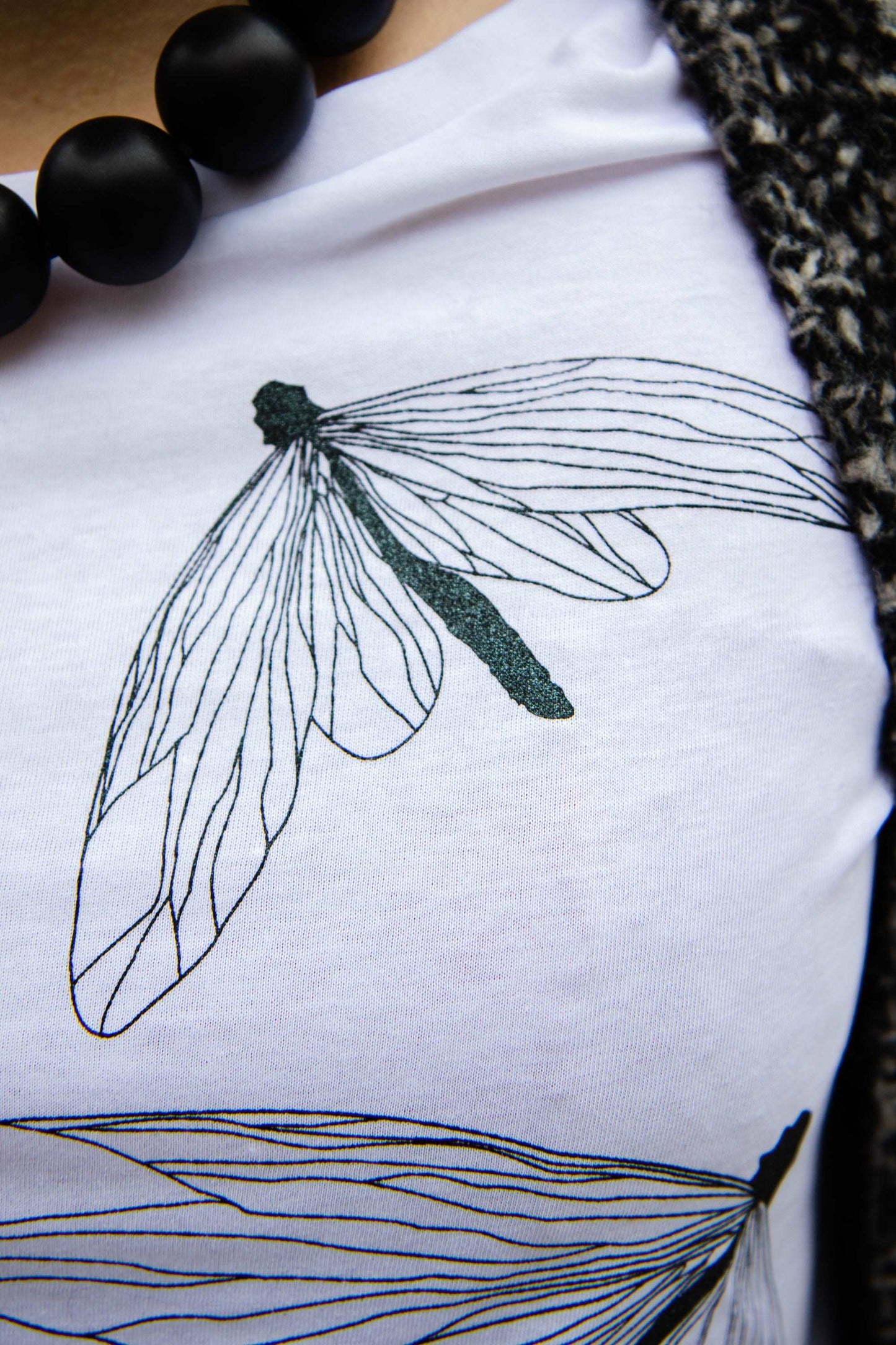 Bela majica s kapuco in potiski bleščečih črnih metuljev